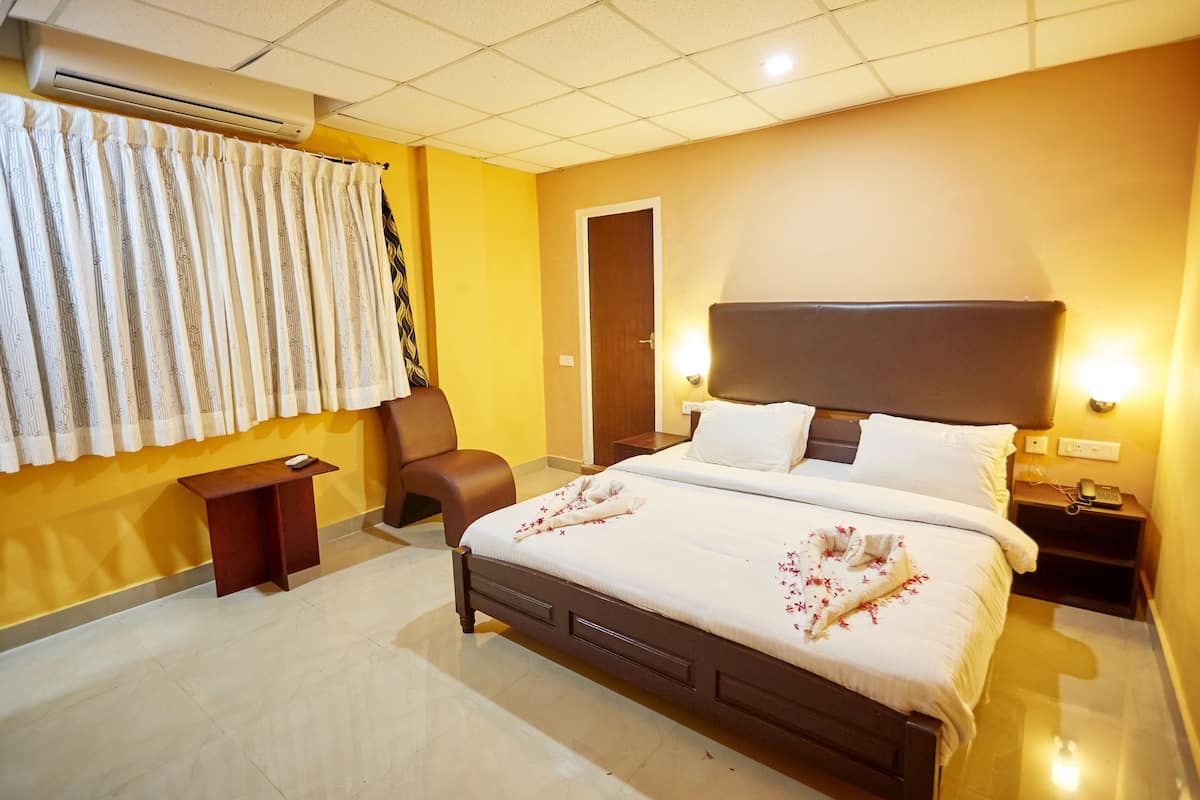 A hotel room with a bed, a chair, a bedside table, and a nightstand.