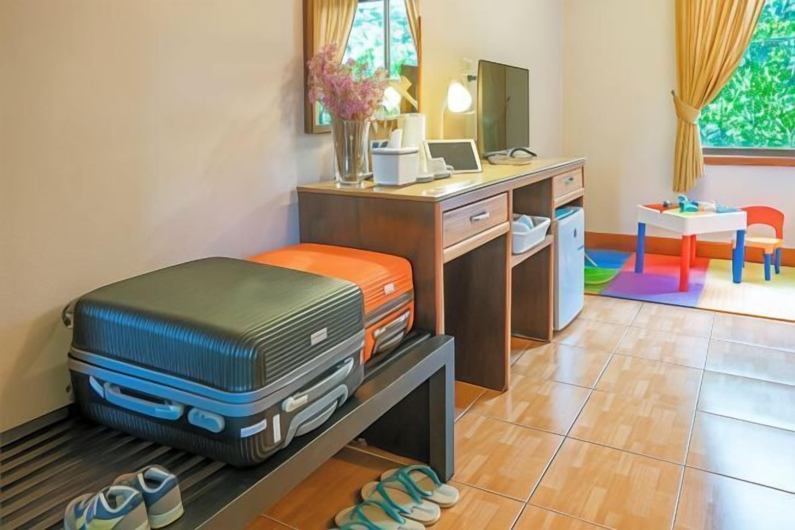 Une petite pièce comprenant un lit, un bureau avec un ordinateur, une chaise et une fenêtre avec des rideaux.