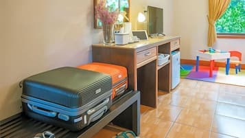 Une petite pièce comprenant un lit, un bureau avec un ordinateur, une chaise et une fenêtre avec des rideaux.