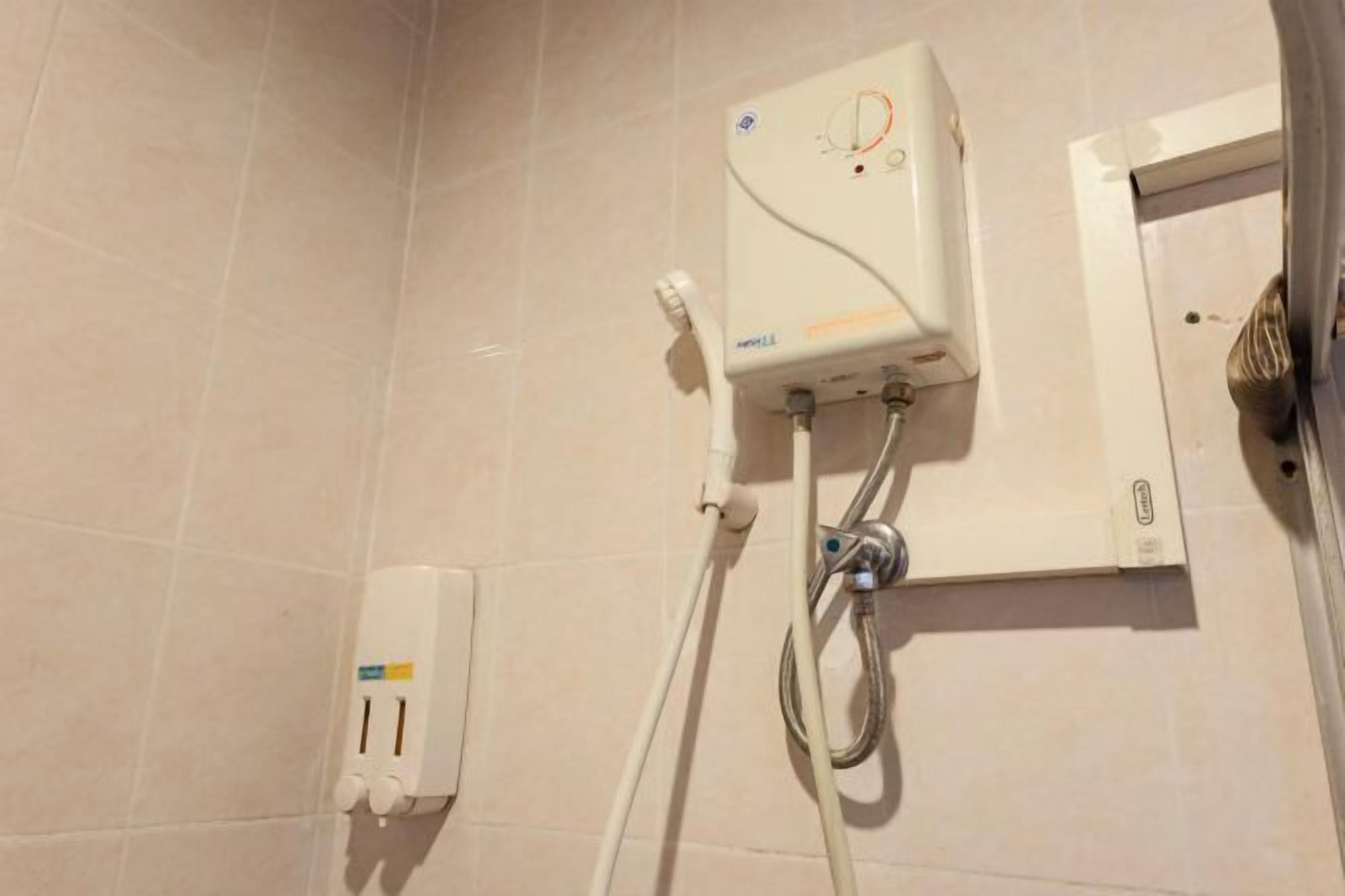 Ein Badezimmer mit einer weißen Duschkabine, einem Handtrockner an der Wand und einer Steckdose.