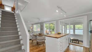 A kitchen with a wooden island, a dining area with chairs, and a view of the outdoors.