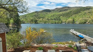 A lakeside patio with lounge chairs and a dock extending into the water.