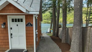A wooden building with a white door, a sign reading '28 Shore Drive,' and a pathway leading to a lake.