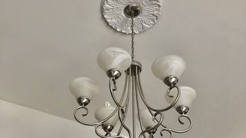 Un candelabro con una placa decorativa central y múltiples brazos con pantallas de vidrio esféricas.