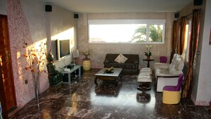 A living room with a marble floor, a sofa, a coffee table, and a TV.