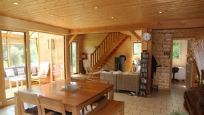 A wooden interior with a dining table, chairs, a staircase, and a bookshelf. - LE CABANON BRETON - Ecogîte with SWIMMING POOL near SAINT-MALO, MONT-ST-MICHEL (Saint-Pierre-De-Plesguen)