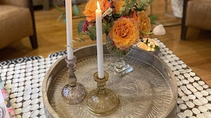 Un salon doté d’une cheminée, d’un téléviseur fixé au-dessus et d’un plateau décoratif orné de bougies et de fleurs.