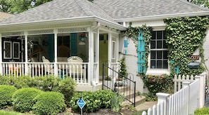 Charming single-story house with a quaint porch and covered entryway, featuring a traditional design with a blue door and window shutters.