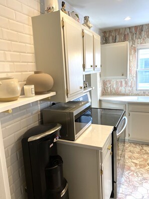 Compact kitchen with microwave, coffee maker, and natural light.