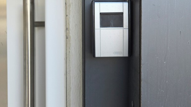 A door with a modern intercom system and a metallic handle.
