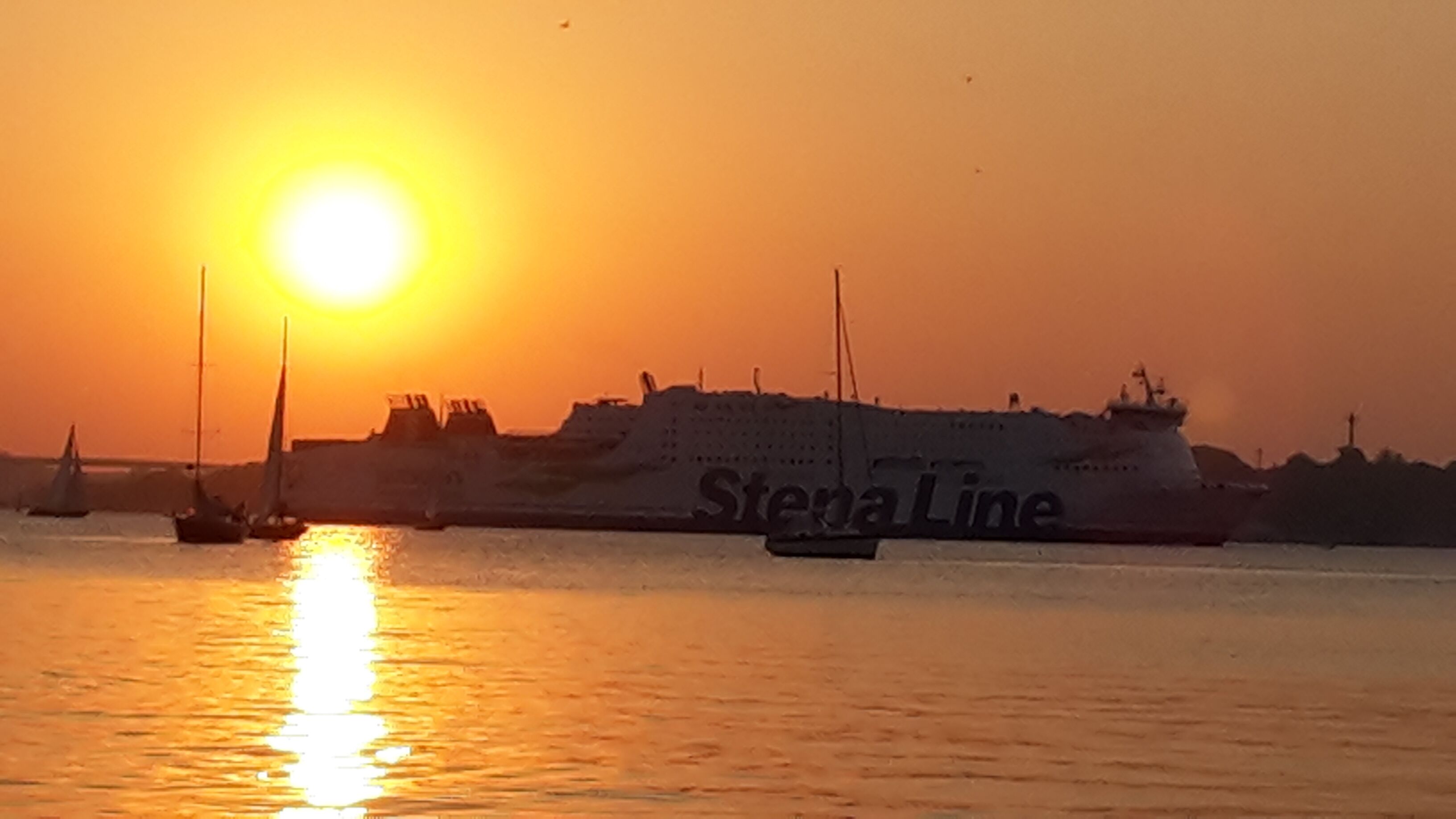 Un gran carguero con el nombre "Stena Line" en el costado, navegando en el agua durante el atardecer.