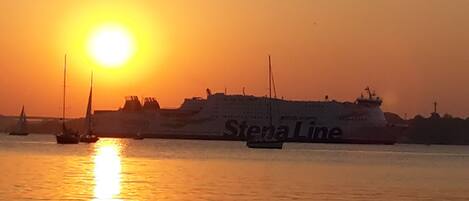 Un gran carguero con el nombre "Stena Line" en el costado, navegando en el agua durante el atardecer.