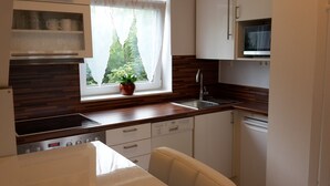 Une cuisine de taille réduite, dotée d’une fenêtre, d’un évier, d’un four à micro-ondes et d’un lave-vaisselle.