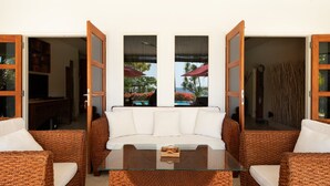 Quarto com mesa de vidro, sofá branco e cadeiras de vime.