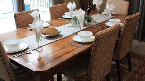 Une table de salle à manger en bois, mise avec de l’argenterie, des assiettes blanches et des serviettes.