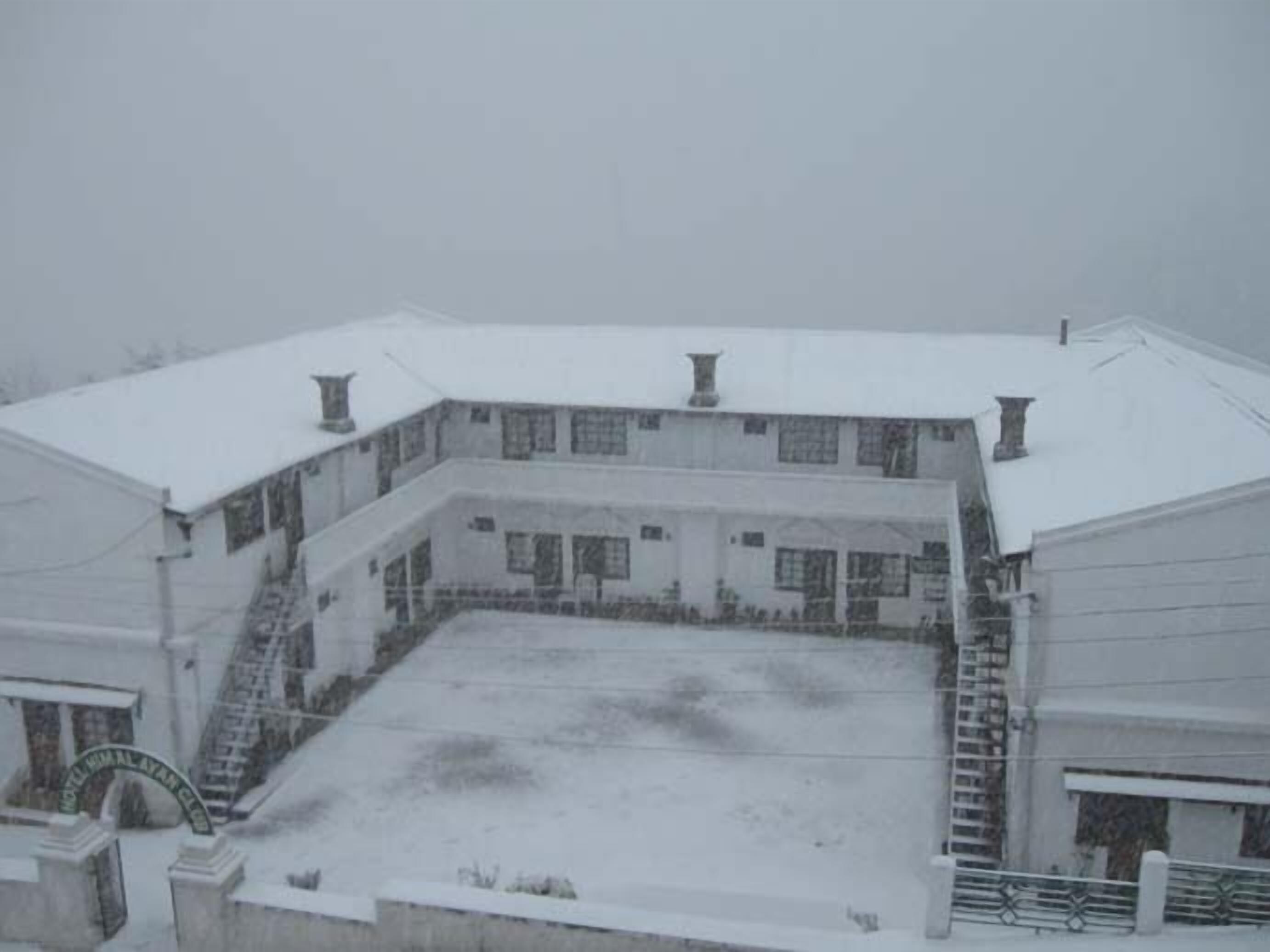 Um edifício de vários andares com telhado coberto de neve e um pátio central.
