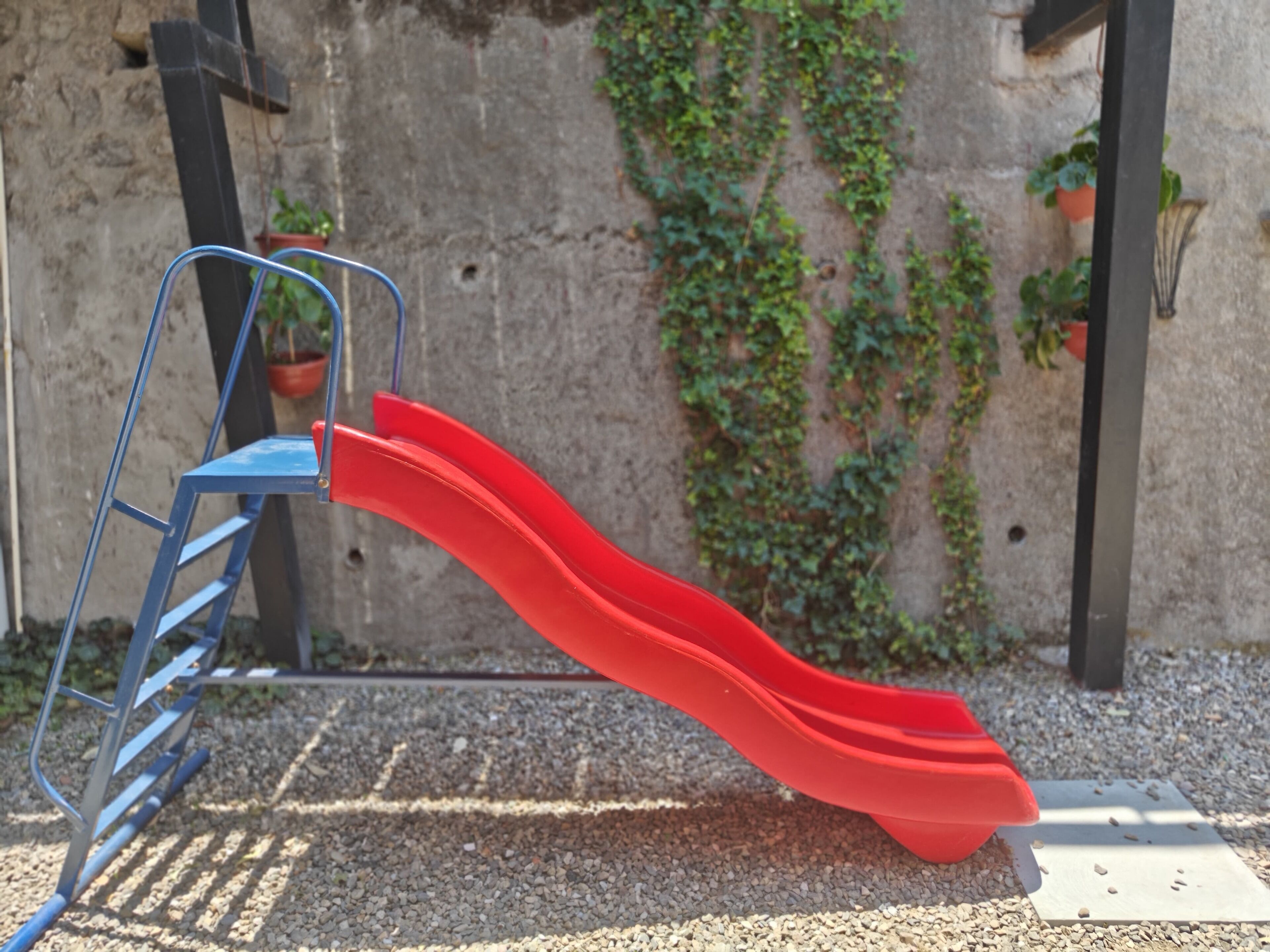 A playground with a red slide and a blue metal structure.