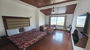 Une chambre spacieuse avec un grand lit, un ventilateur de plafond, un canapé, une table et un téléviseur.