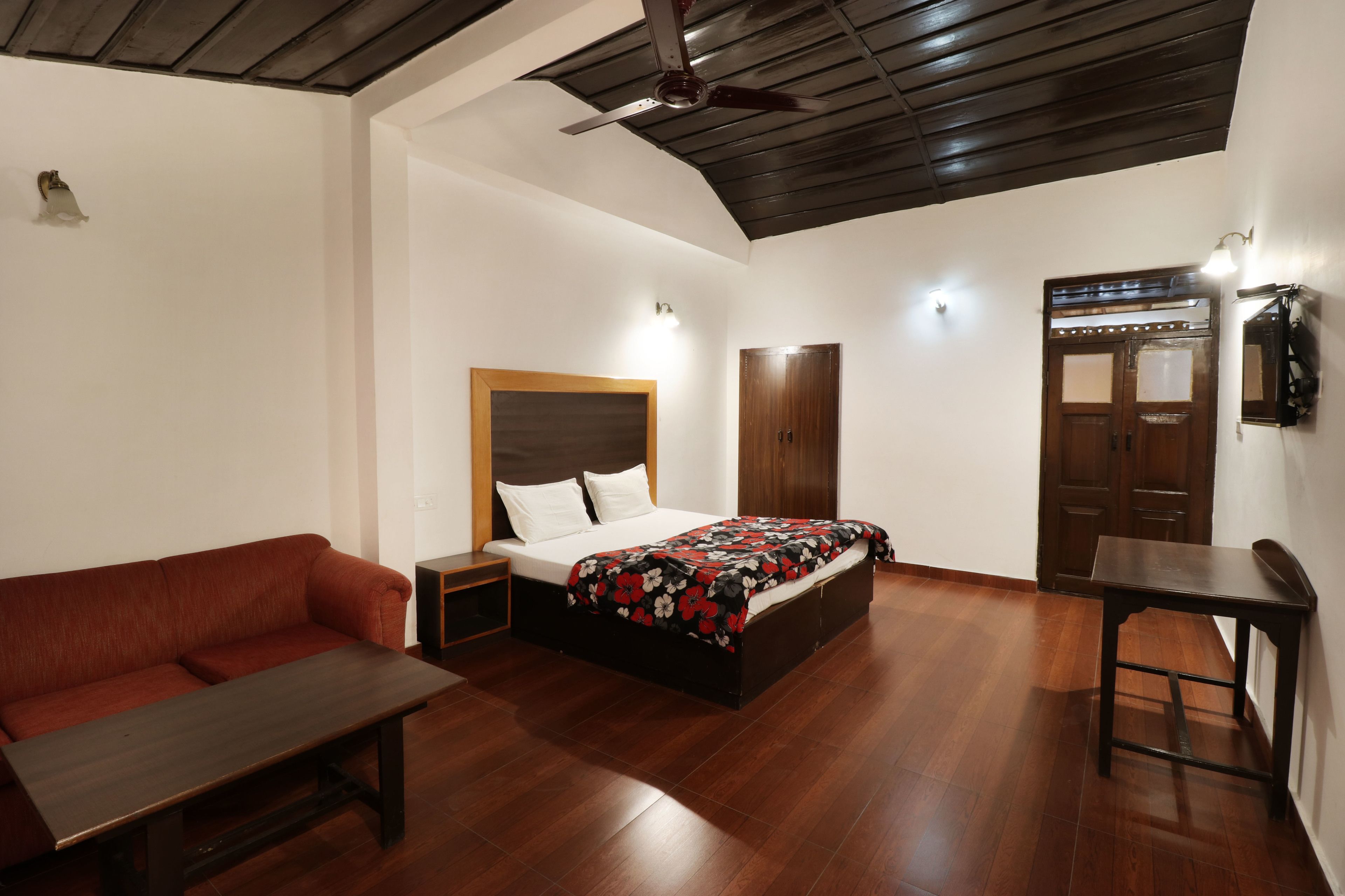 Un dormitorio con cama, banca de madera, mesita de noche, armario y mesa.