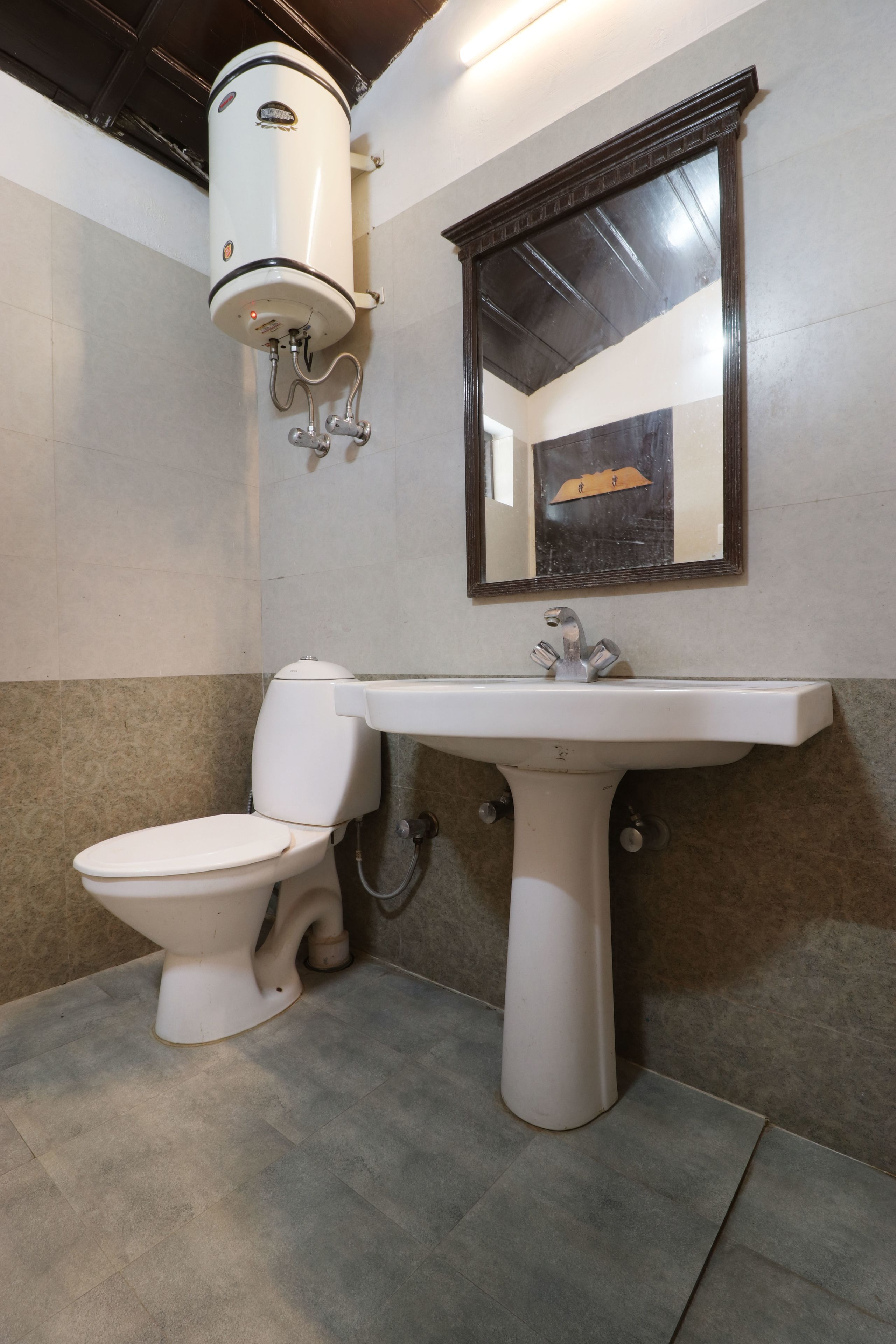 A bathroom with a toilet, a pedestal sink, and a wall-mounted heater.