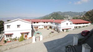 Un bâtiment blanc avec un toit rouge, un escalier et une enseigne sur laquelle on peut lire « Hôtel Himalayan Club ».