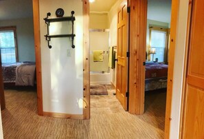 Un pasillo con una puerta de madera que da a un dormitorio con cama y mesita de noche.