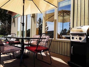 Un patio exterior con mesa y sillas, una parrilla y vistas del entorno.