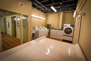 A laundry room with a washing machine, dryers, and a folding table. - Amazing Beach & Sunset Views, Free Lazy Days Beach Chairs/Umbrella provided (Pensacola Beach)