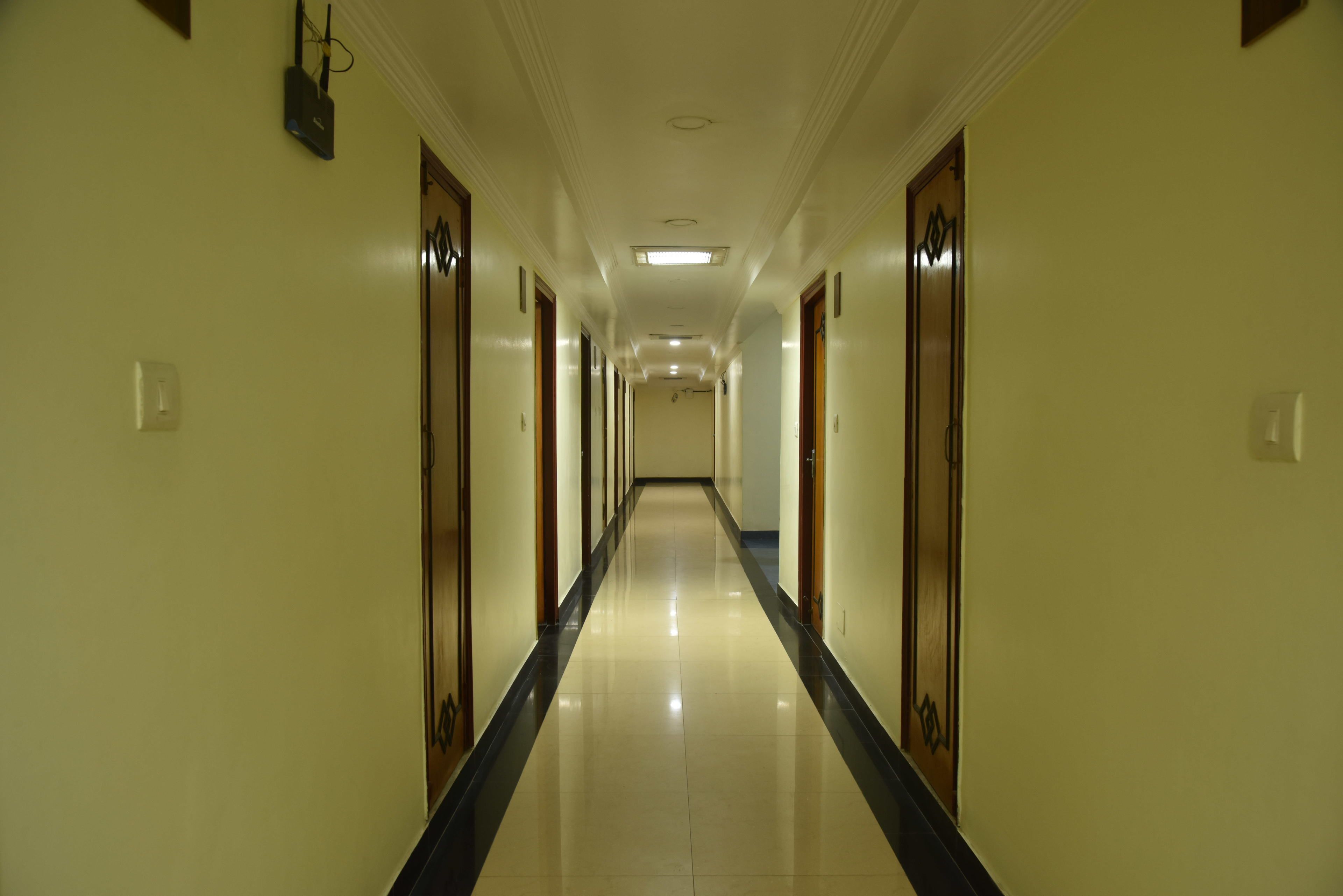 A long, narrow hotel corridor with doors on both sides and a central walkway.