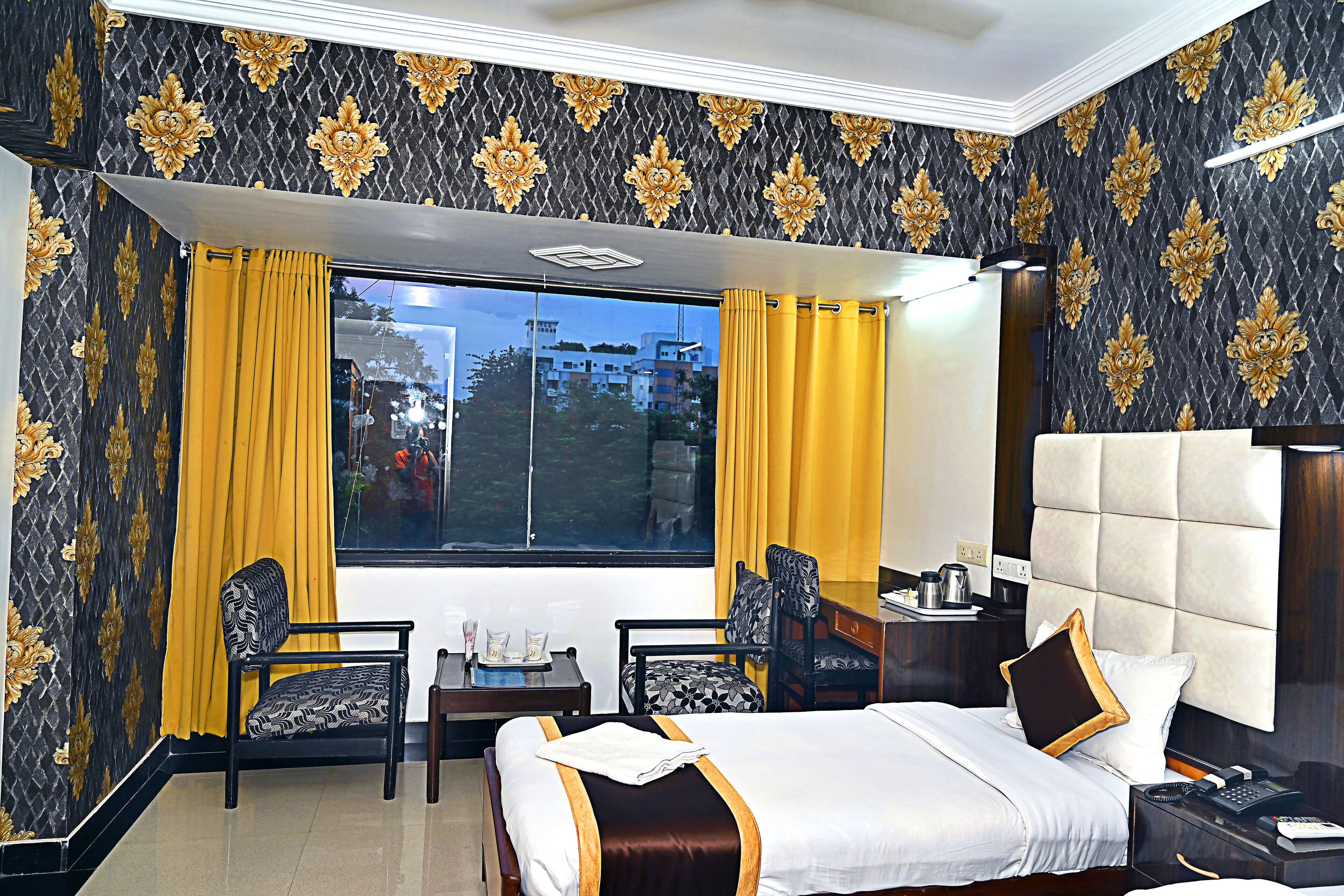 Habitación de hotel con una cama grande, dos sillones, una mesita y vistas al exterior.