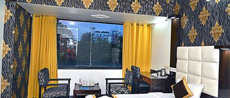 Habitación de hotel con una cama grande, dos sillones, una mesita y vistas al exterior.