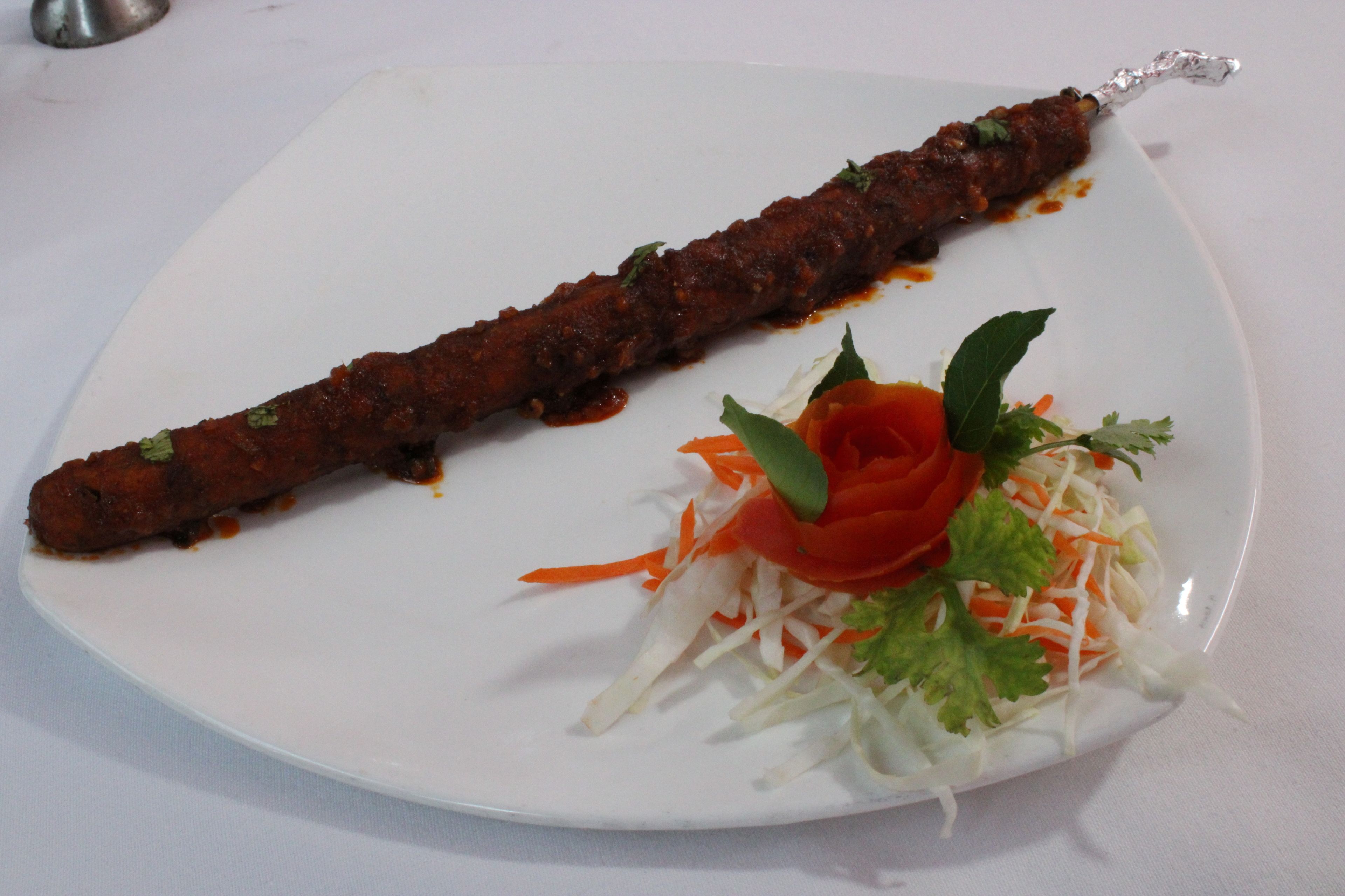 Une assiette avec une brochette de viande et une salade.