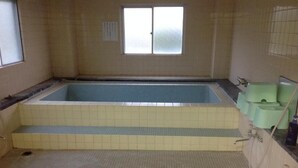 Une salle de bain avec une grande baignoire, une fenêtre et un sol carrelé.