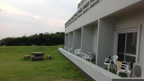 Un bâtiment doté d’un balcon, d’un espace extérieur aménagé pour s’asseoir et d’une pelouse.