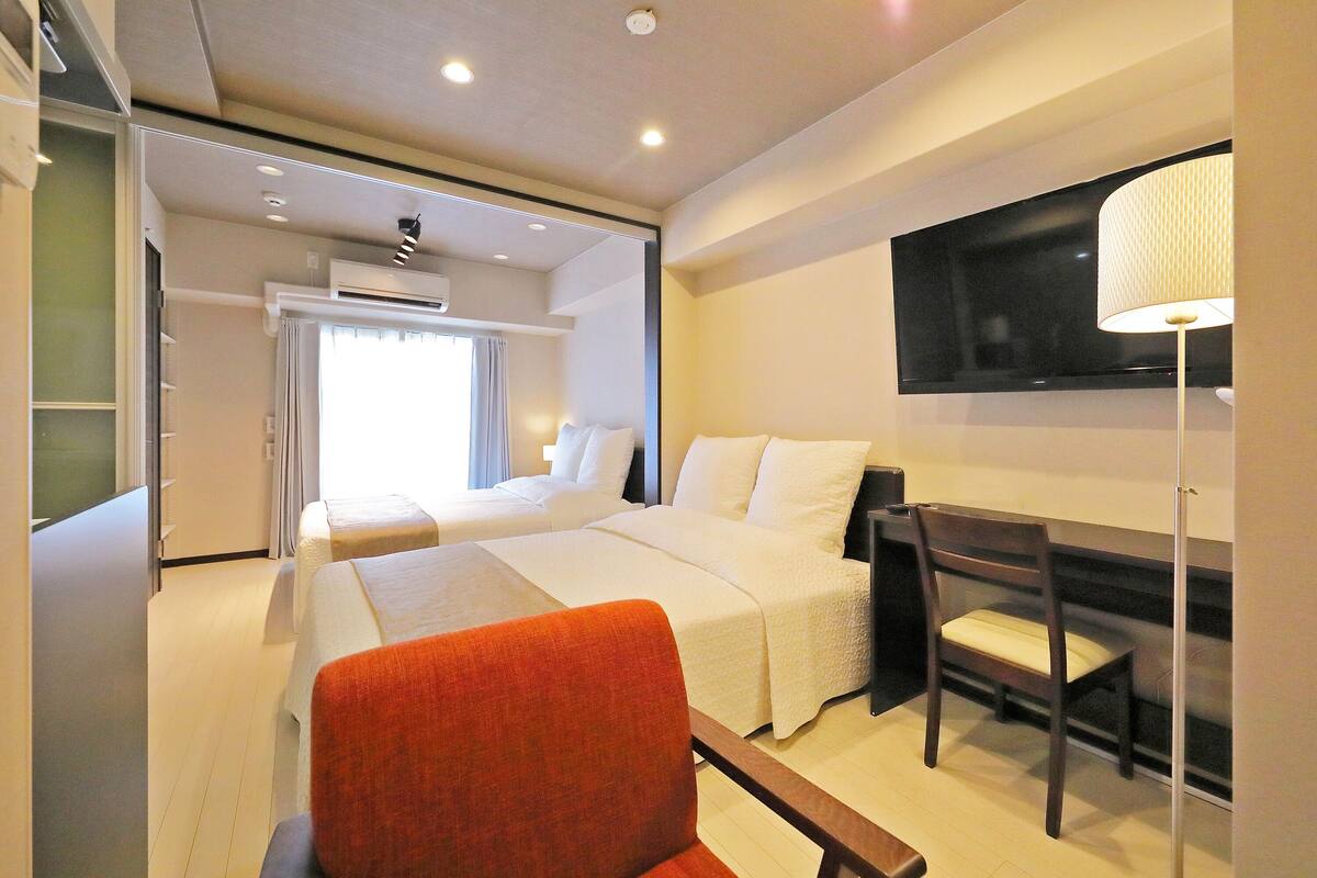 Une chambre d’hôtel comprenant un lit, un bureau, une chaise, une télévision et une armoire.
