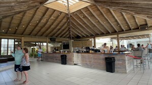 Et spiseområde indendørs med højt til loftet og træbjælker, der indeholder en bar og siddepladser.