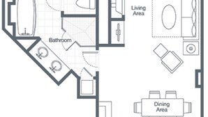 Un plan d’étage d’une chambre d’hôtel comprenant une chambre principale, un balcon, un espace de vie, un coin repas, une cuisine et une salle de bain.