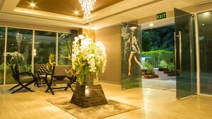 A modern lobby with a chandelier, seating area, and an exit sign. - The Near Residence - Sriracha (Si Racha)