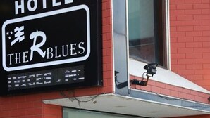 A hotel sign with "HOTEL THE R BLUES" and a digital display. There are potted plants in front. - Hotel The R Blues (New Delhi)