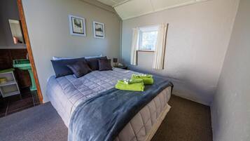 A bedroom with a bed, a nightstand, a window, and a mirror.