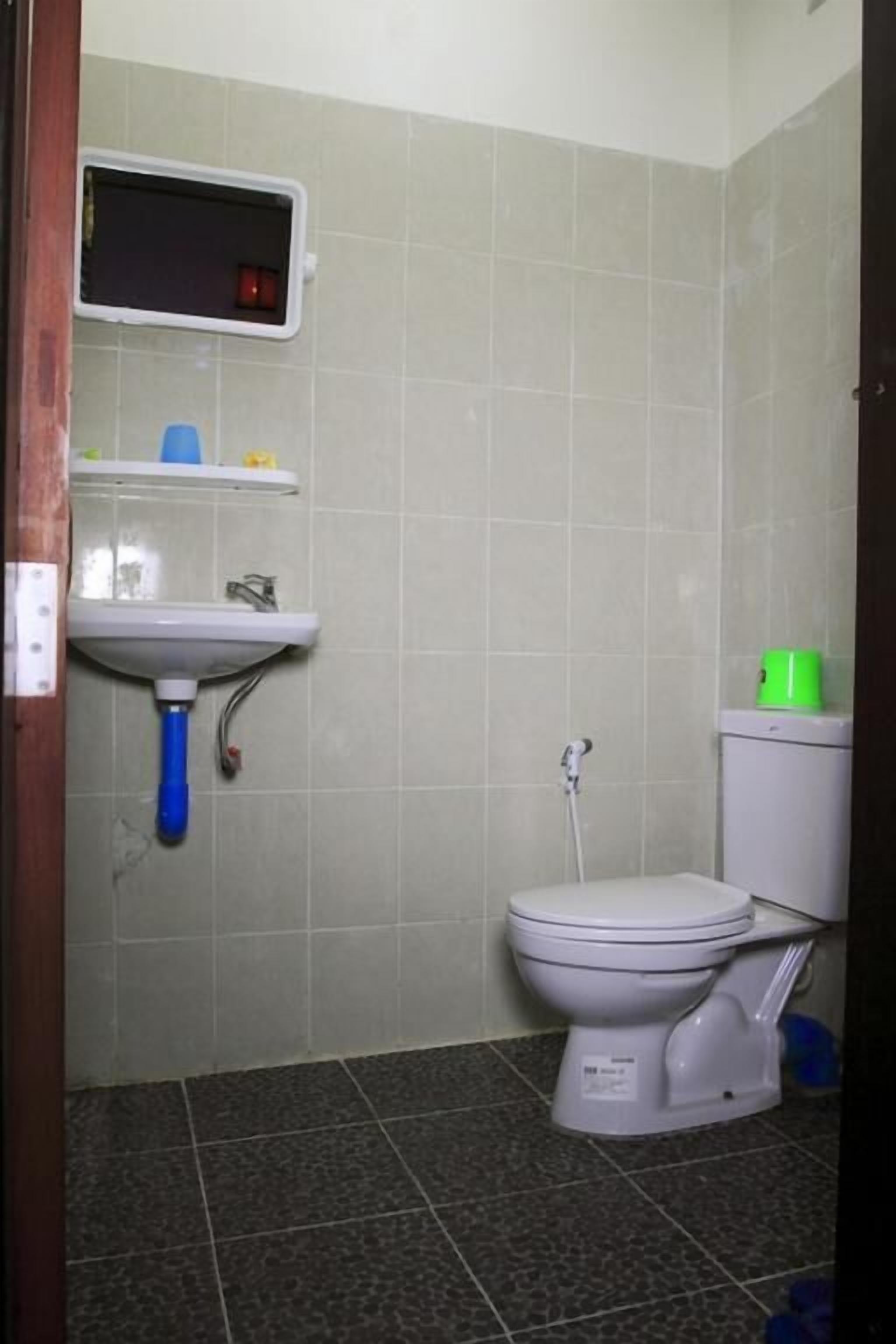 Een kleine badkamer met toilet, wastafel en spiegel.