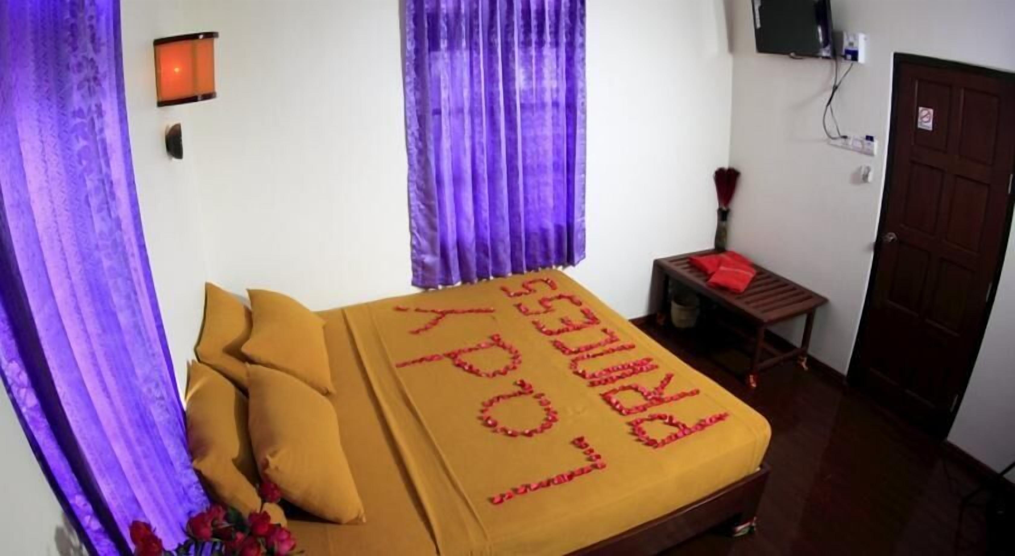 Una habitación con una cama, una mesita, un televisor y una puerta.