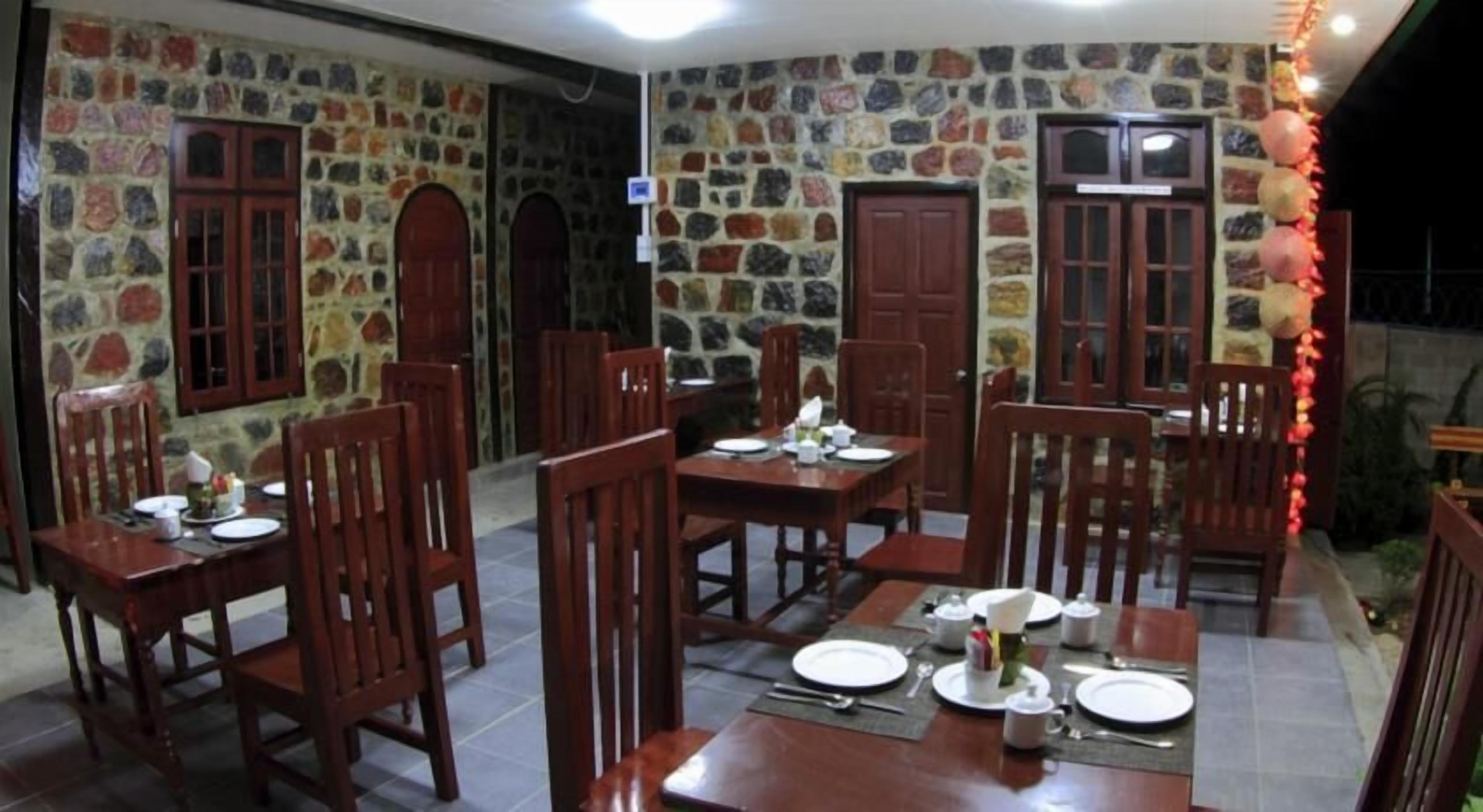 A dining area with stone walls, wooden furniture, and a tiled floor.