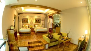 Habitación de hotel con dos camas, un sofá, un televisor y una zona de comedor.