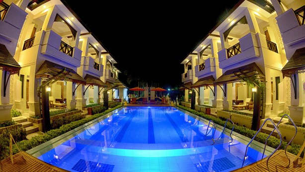 Una piscina con muelle de madera, rodeada por edificios de dos pisos con balcones y terrazas al aire libre.