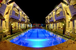 A swimming pool with a wooden deck, surrounded by two-story buildings with balconies and outdoor seating areas. - Shwe Taung Tan Hotel Lake View (Monywa)