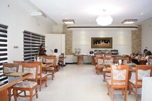 A spacious dining area with wooden tables and chairs, a central buffet station, and a decorative wall with a framed artwork. - Shwe Taung Tan Hotel Lake View (Monywa)