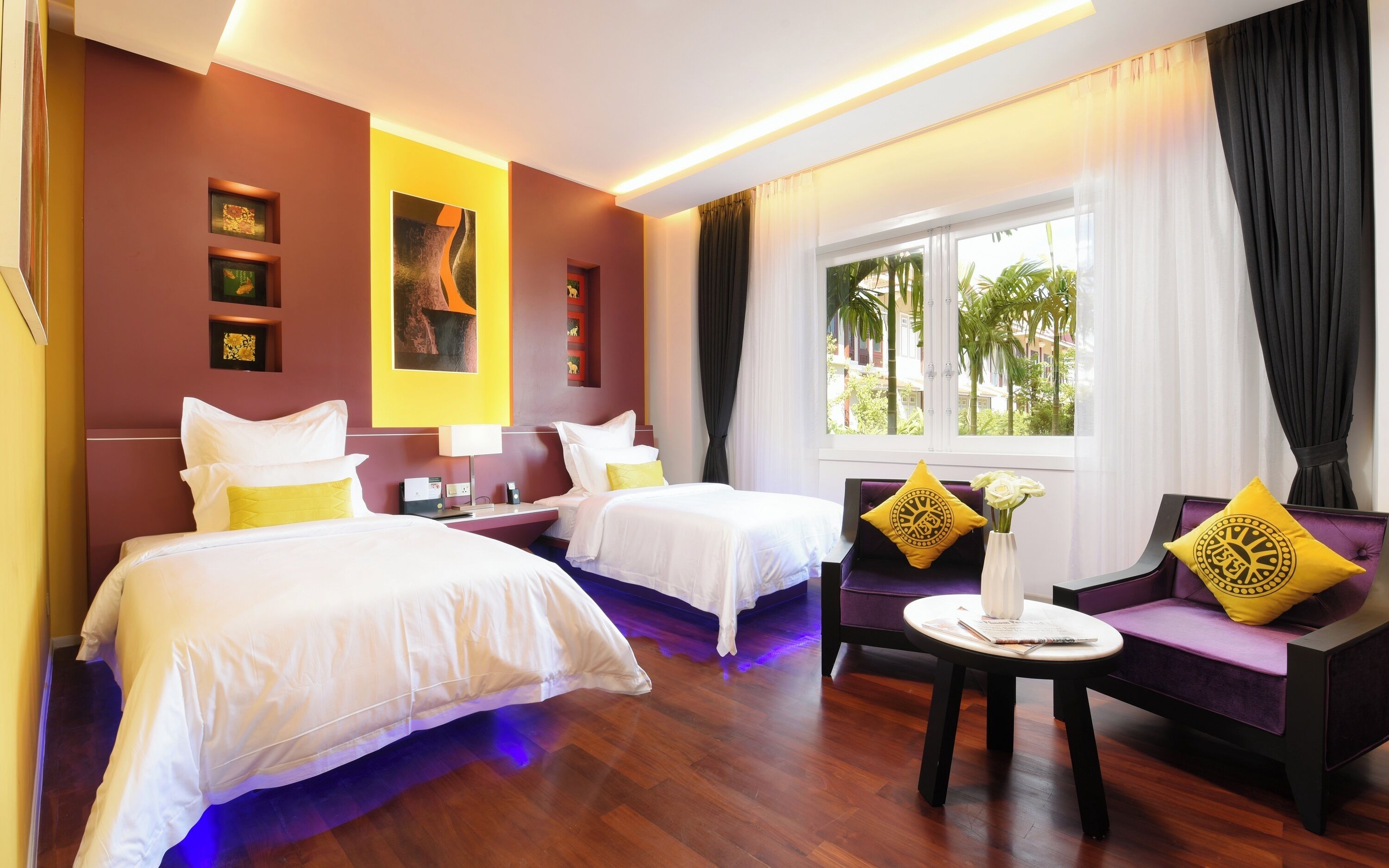 A hotel room with two beds, a sofa, a small table, and a window with curtains.