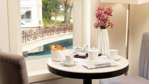 A breakfast table with a vase of pink flowers, a newspaper, and various breakfast items. - Memoire Palace Resort & Spa (Siem Reap)
