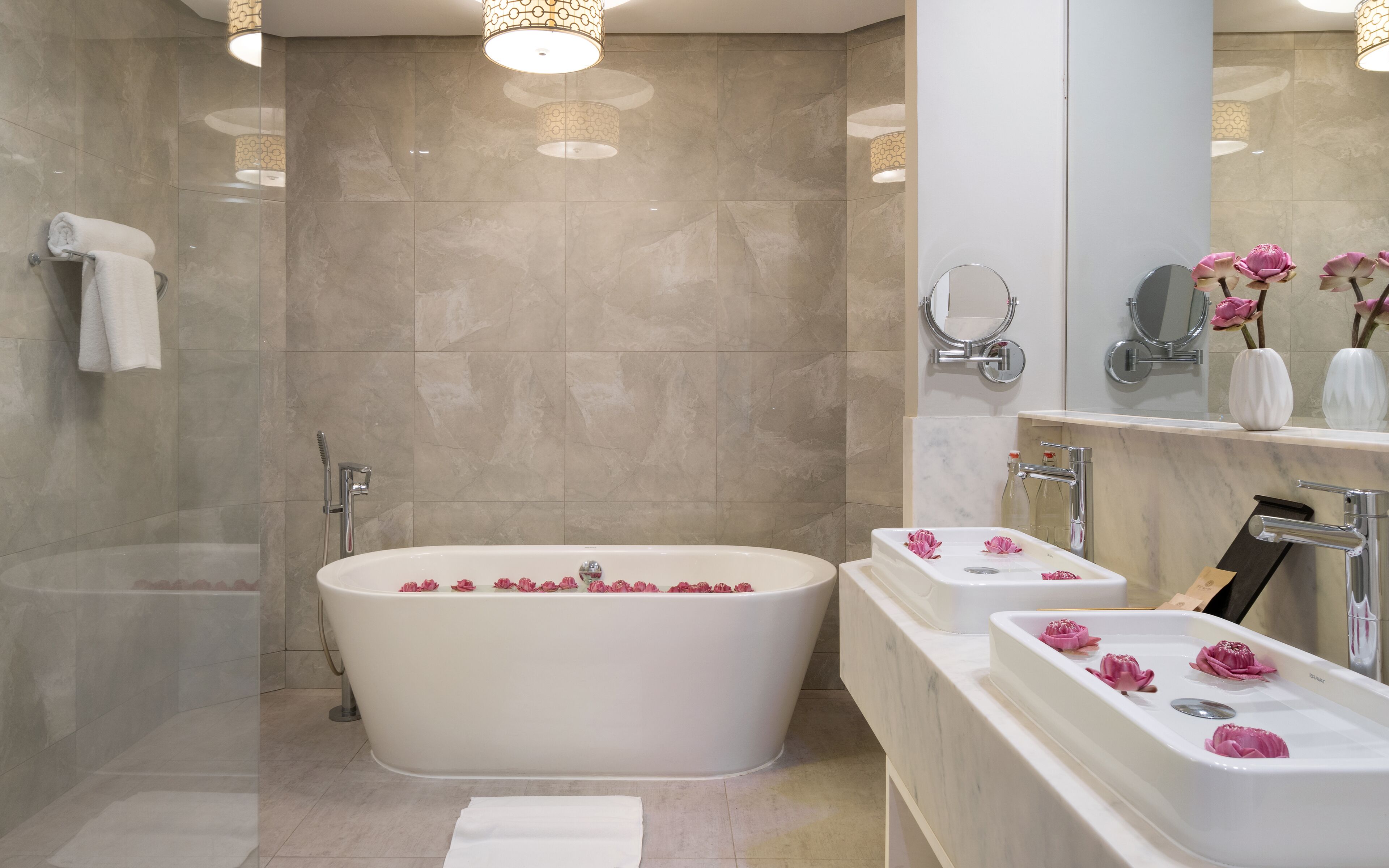 A modern bathroom with a freestanding bathtub, two sinks, and a large mirror.